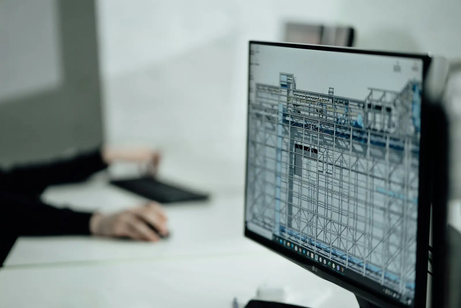 A person reviewing work at a desk with a monitor